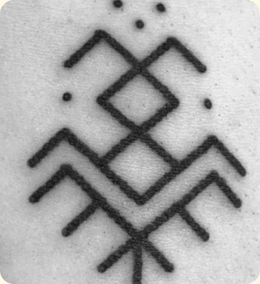 A गोंदण tattoo of diamonds and chevrons inked on skin.